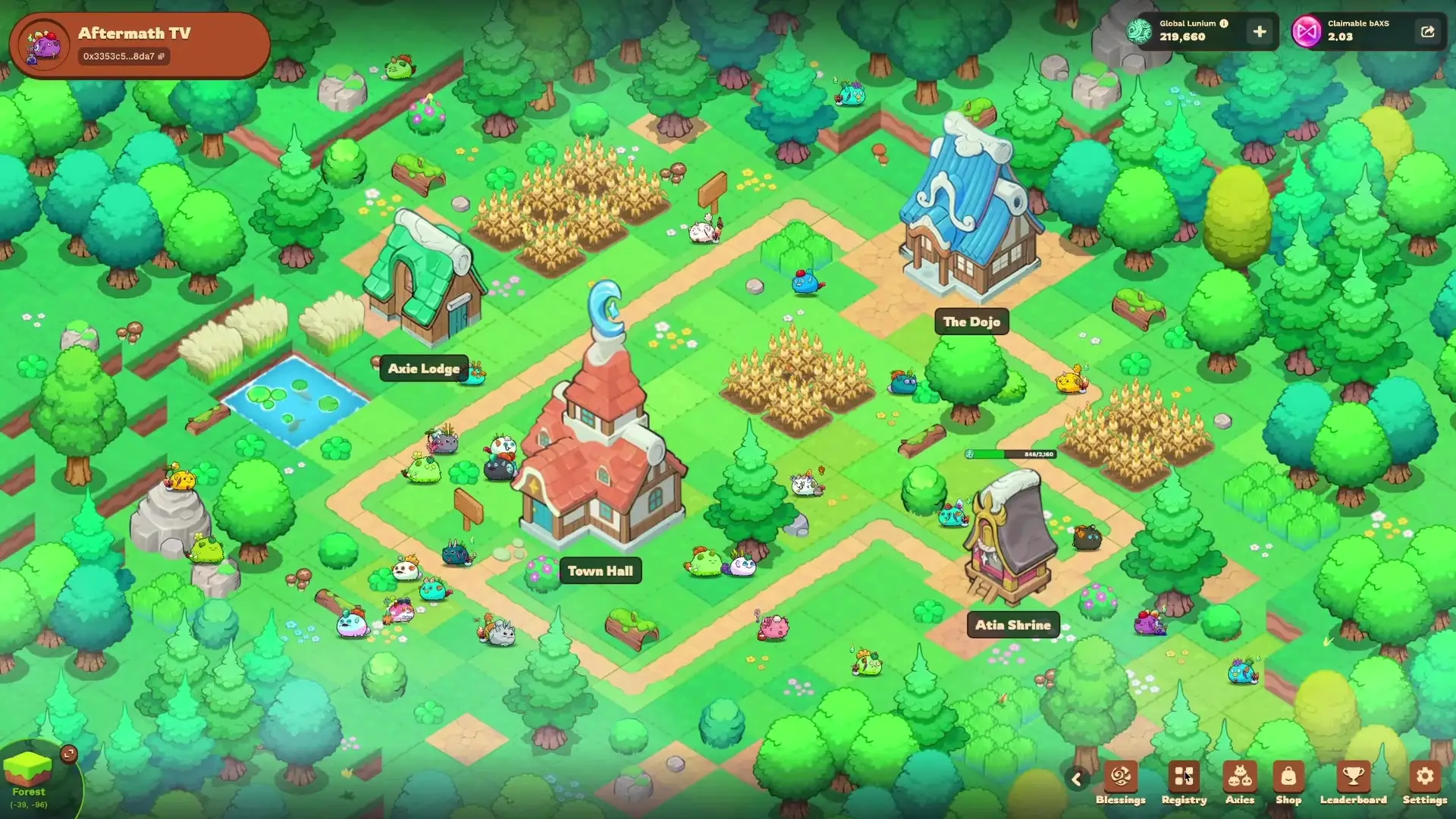 In Axie Infinity: Terrariums, numerous colorful creatures wander through a vibrant green landscape featuring buildings labeled Town Hall, The Dojo, and Atia Shrine alongside patches of crops and trees.
