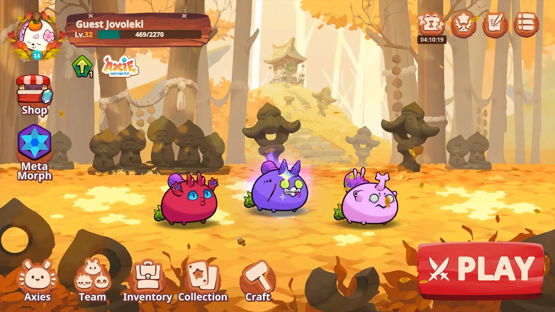 In Axie Infinity, three colorful character creatures with unique features stand on a path covered with autumn leaves, set against a background of trees and stone sculptures.
