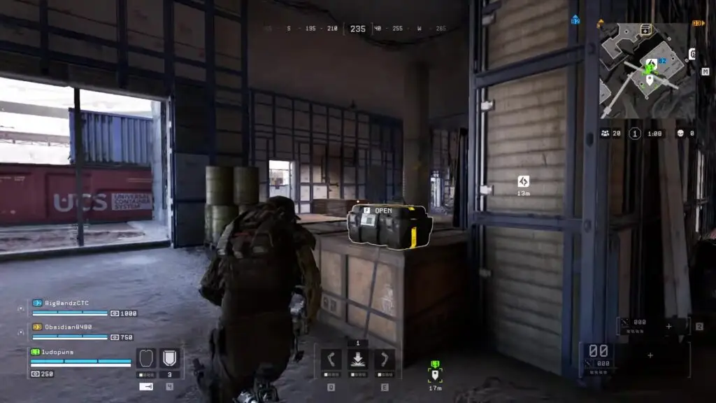 A screenshot from Off The Grid showing a third-person soldier exploring an industrial warehouse filled with shipping containers and crates, with a highlighted loot box, teammate indicators, a minimap, and on-screen combat controls.